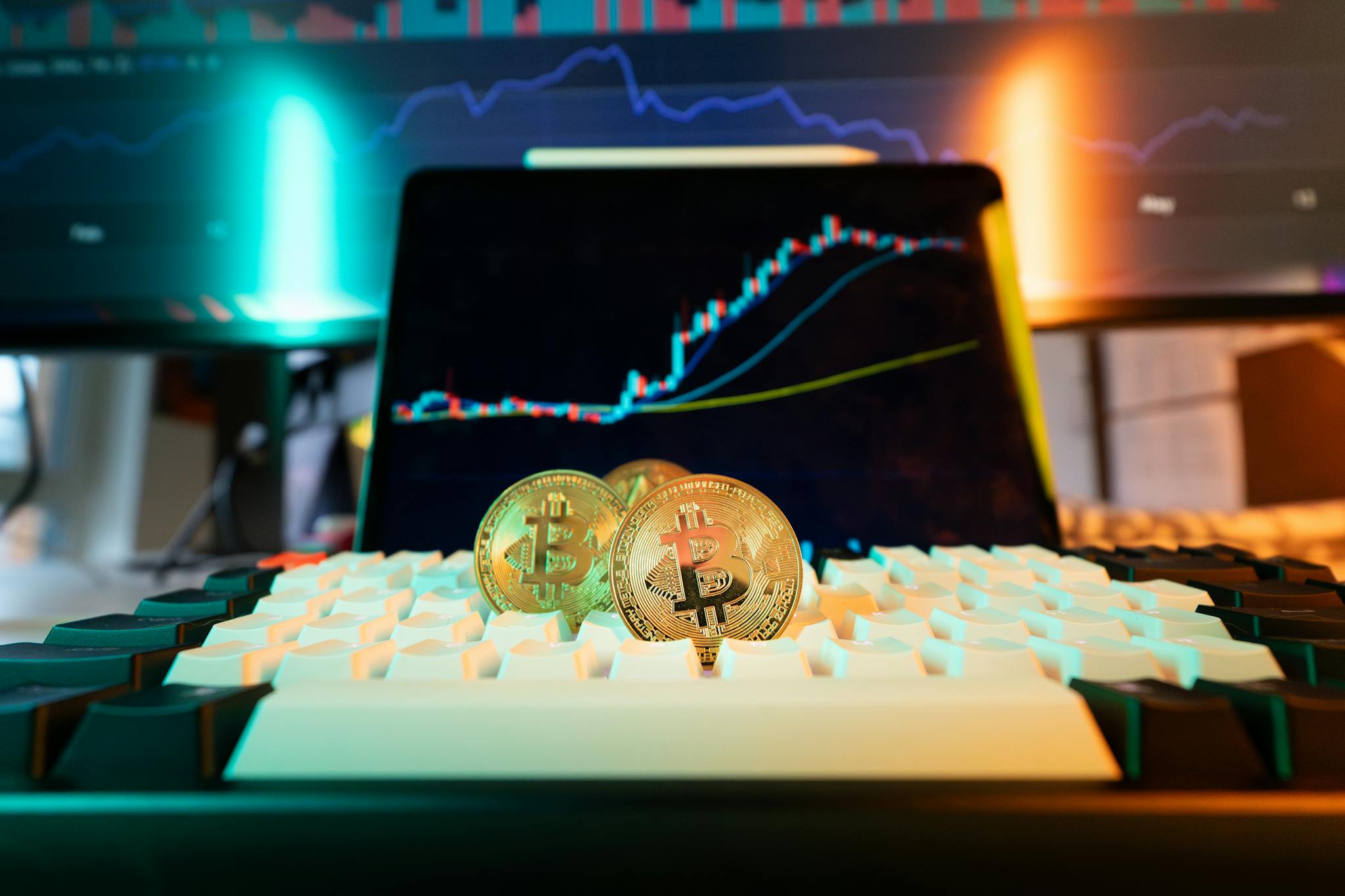 Close-up of Bitcoin coins on a keyboard with a trading chart in the background